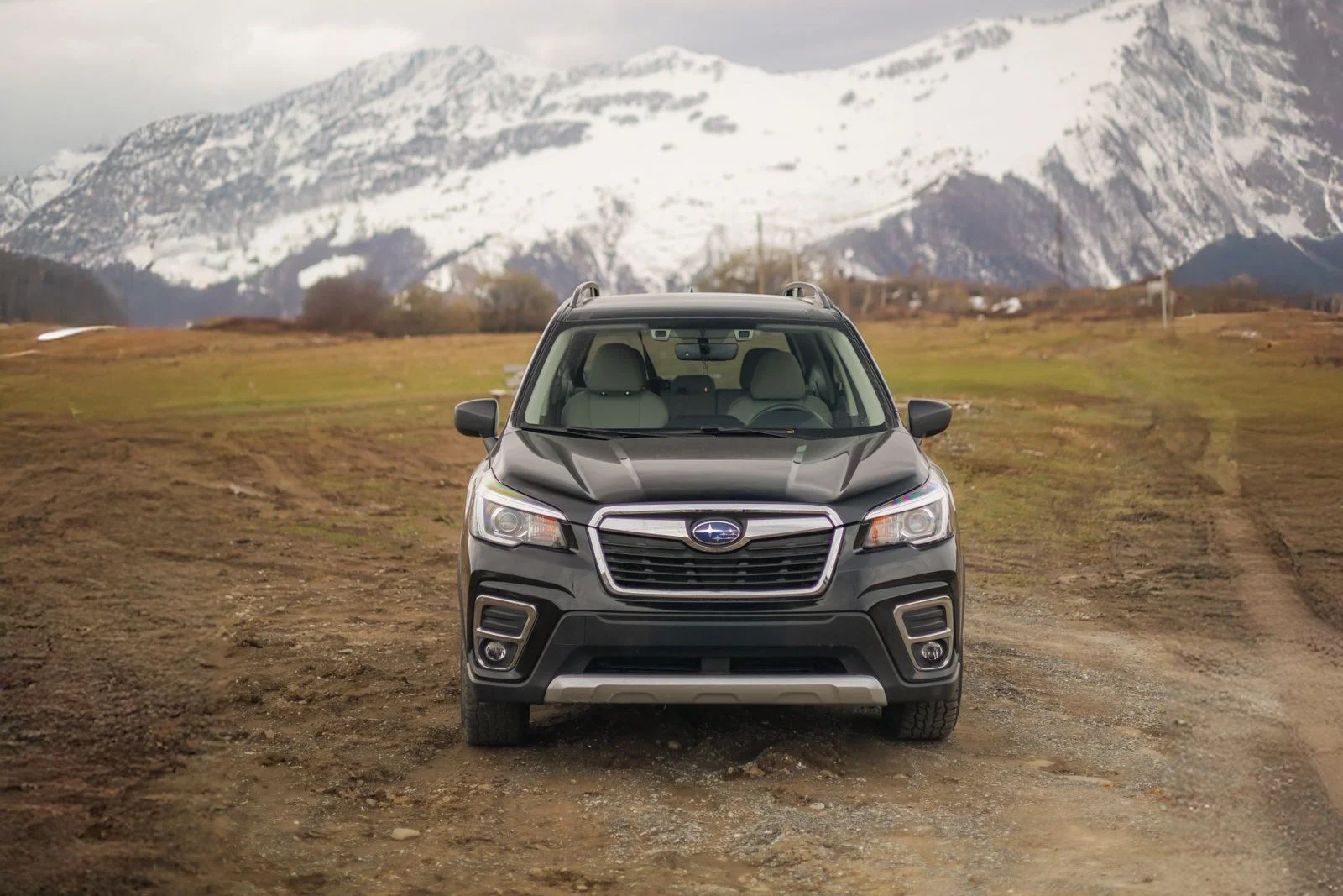 A Subaru Forester in snow with mountains behind