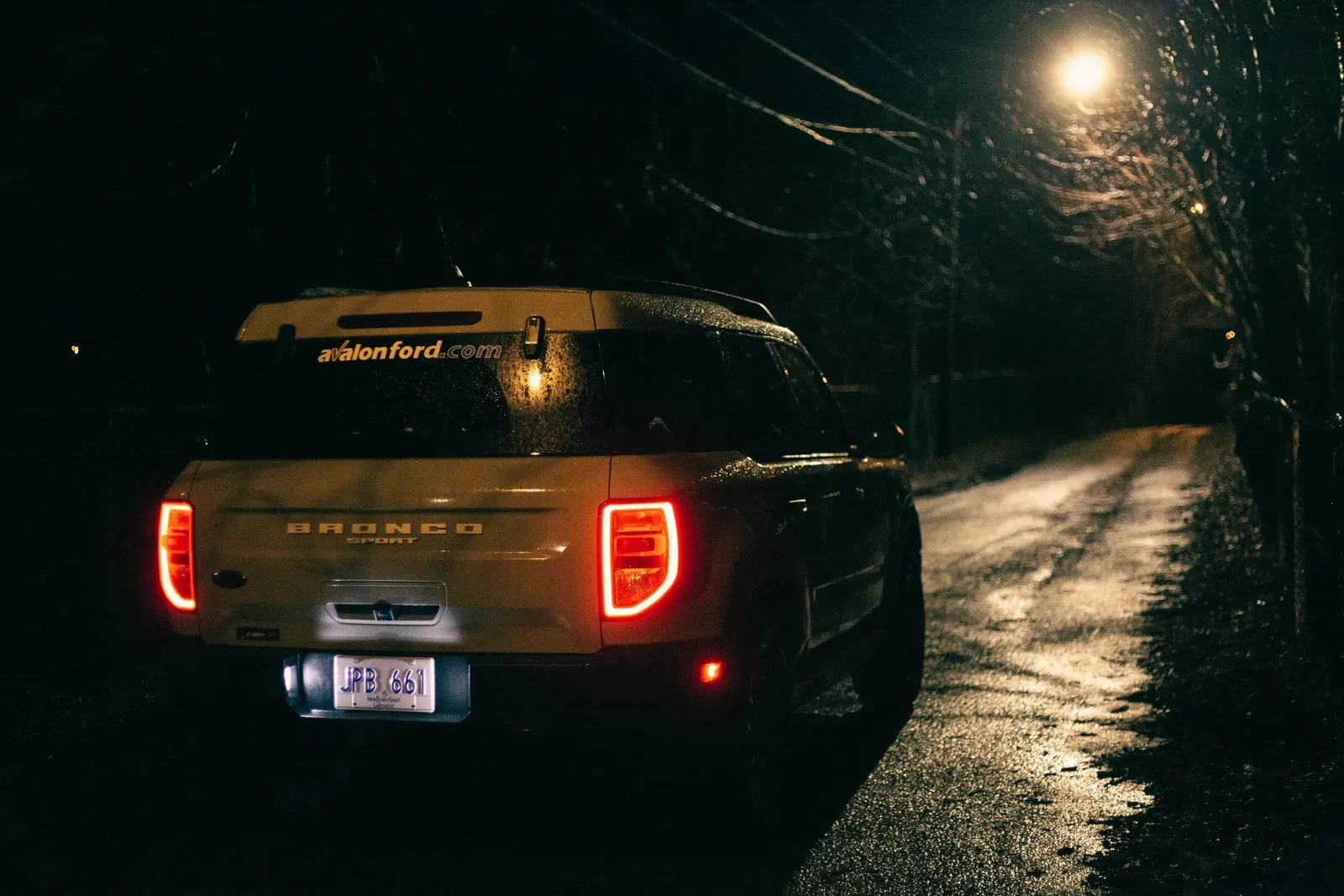 A white Ford Bronco Sport on a wet road at night
